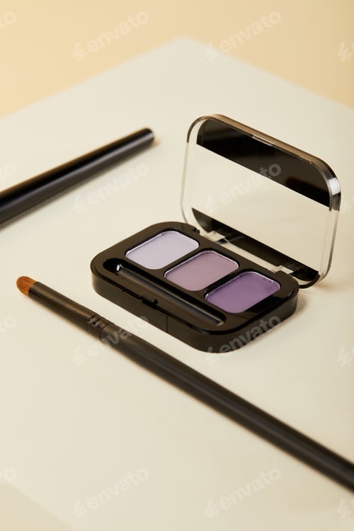 Preview: close-up shot of purple eyeshadows case with brush on beige