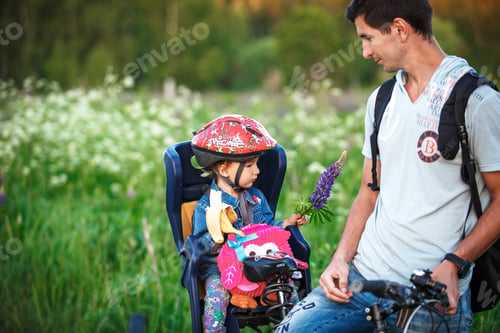 Preview: Father with a small daughter in a children's bicycle seat on an adult bicycle