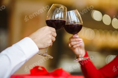 Preview: Couple clink glasses with red wine. Lovers give each other gifts. Lovely romantic dinner.