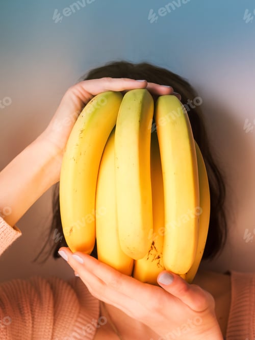 Preview: Woman Holding Bunch of Yellow Bananas to Face