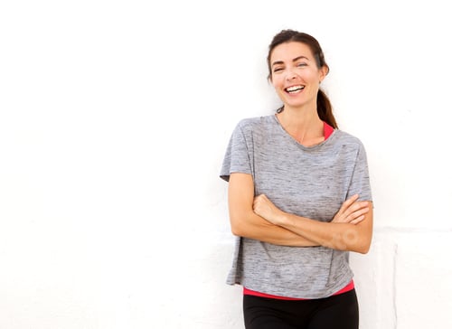 Preview: attractive young sports woman smiling with arms crossed against white wall