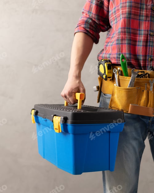 Preview: Worker man holding construction toolbox near concrete or cement wall. Male hand and tool box