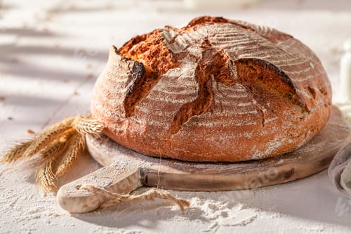 Preview: Homemade round loaf bread on wooden cutting board.