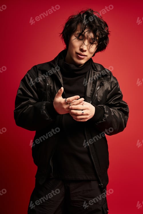 Preview: Lost in thought asian man posing in stylish black outfit in studio