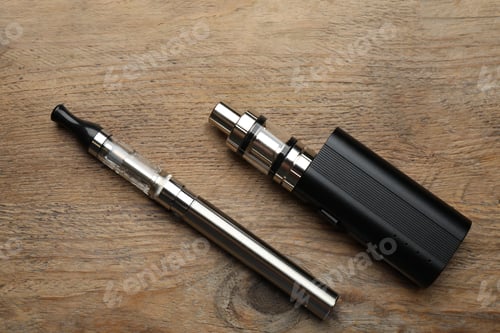 Preview: Different electronic cigarettes on wooden table, flat lay. Smoking alternative