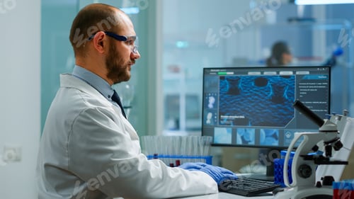 Preview: Scientist in lab coat analysing blood sample from test tube