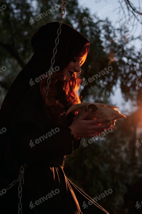 Preview: Woman disguised as a witch holding a skull in her hands