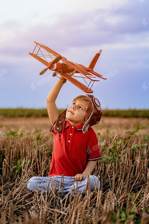Preview: Smiling interested 5 years old child boy playing with wooden airplane, discovering future