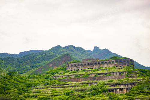 Preview: ancient Buildings on a green hill surrounded by bushes and taller mountains