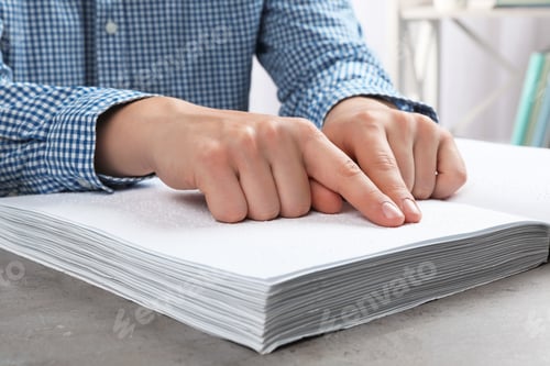 Preview: Blind person reading book written in Braille at table, closeup