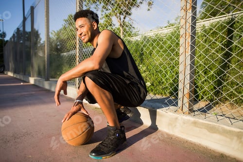 Preview: Young man on basketball court, crouching with ball