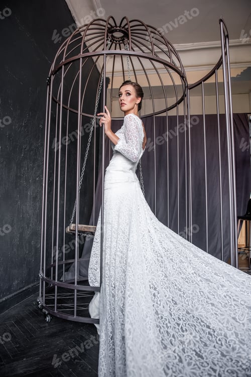 Elegant Woman in White Dress Stands in Cage