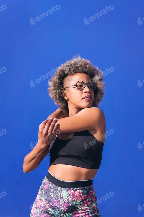 Preview: african sportswoman stretching in blue background