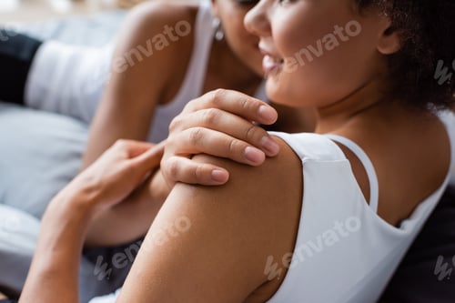 Preview: cropped view of african american lesbian woman hugging happy girlfriend in bedroom