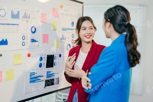 Preview: Two young businesswomen discussing new company strategy, brainstorming and analyzing marketing data