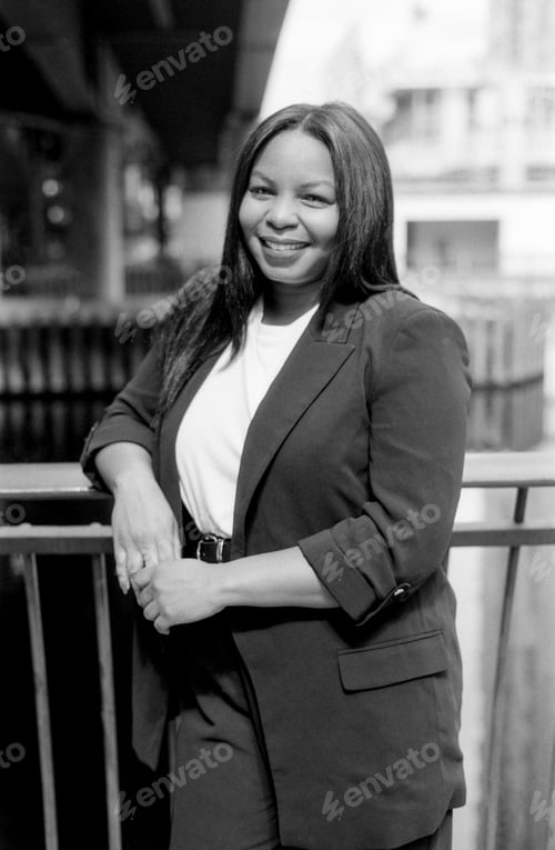 Preview: Smiling businesswoman leaning on railing in urban setting, monochrome portrait