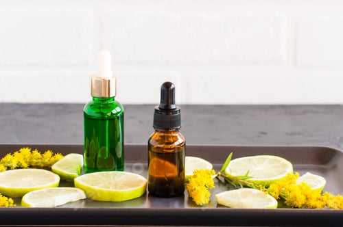 Visualização: dois frascos com uma pipeta com um produto cosmético feito de limão e lima para cuidados com o rosto e o corpo.