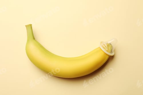 Preview: Sex education. Banana with condom on beige background, top view