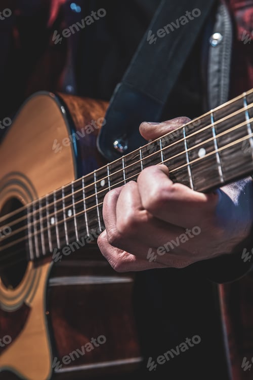 Preview: Guitarist playing acoustic guitar in the dark close up.