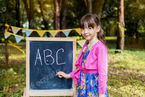 Preview: A little girl is studying near the blackboard. Back to school. The concept of education