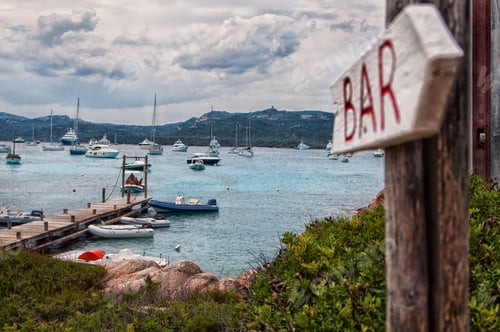 Preview: Shot of an arrow showing where the bar is in the background of the port during a cloudy day.