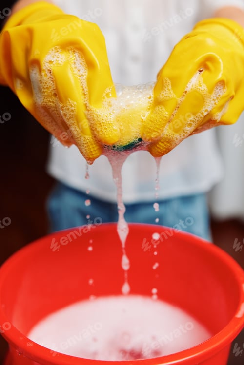 Preview: Woman in yellow rubber gloves holding bucket of soapy water and sponge
