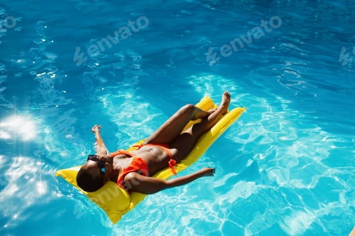 Preview: Sexy woman swims on mattress in the pool, top view