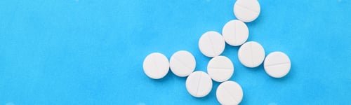 Preview: Several white tablets lie on a bright blue background in the form of a bacteriu