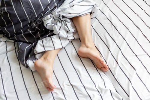 Preview: Young woman sleeps in bed, feet in frame, bed vibes