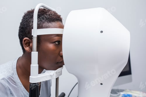 Preview: Black woman in optometry cabinet using a modern corneal topographer