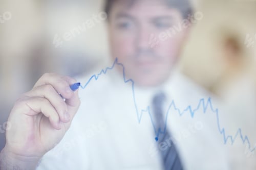 Preview: Recording his business growth. Shot of a businessman writing on a clear wall with a blue pen.