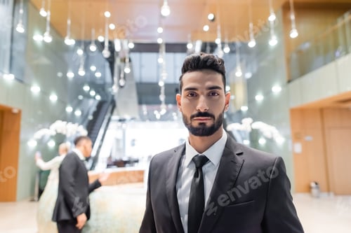 Preview: young bi-racial security man looking at camera near senior woman with bodyguard on blurred