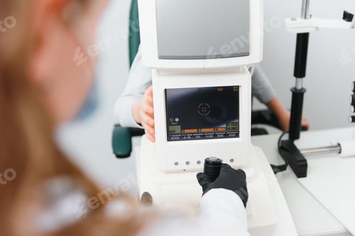 Preview: Close up of ophthalmologist using auto refractometer while examining child eyes.
