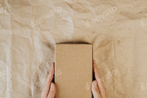 Preview: Male hands holding cardboard box. Top view, layout. Delivery concept. Place for text, logo, ads