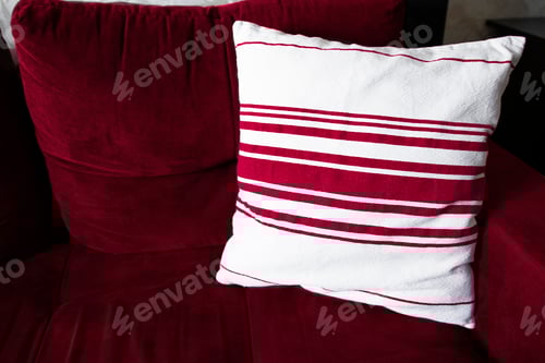 Visualização: Interior da sala de estar com sofá e travesseiro decorativo em close-up. Cor magenta Viva do ano 2023