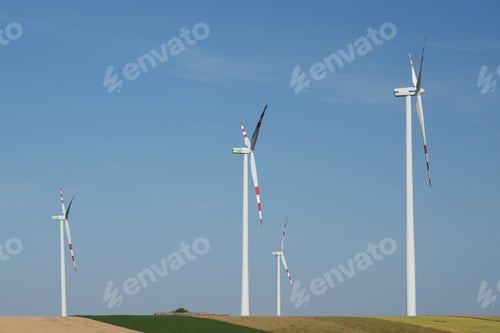 Preview: Four modern wind turbines under a clear blue sky in a field. Austria.