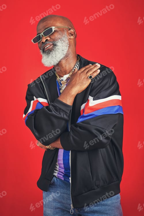 Preview: Studio shot of a senior man wearing retro attire while posing against a red background