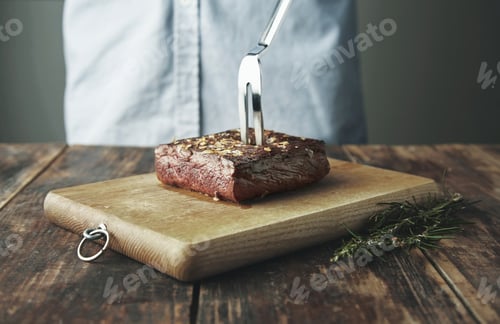 Preview: grilled meat with steel fork isolated on board near herbs