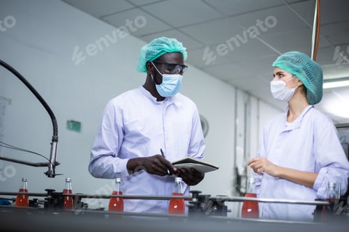 Preview: Factory worker inspecting drink bottle on bottling line