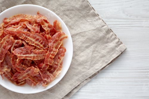 Preview: Crispy Fried Bacon on a white plate, top view. Flat lay, overhead, from above. Space for text.