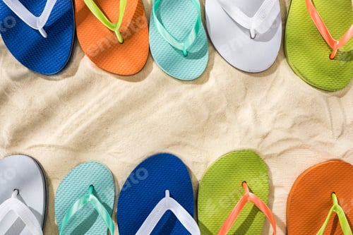 Preview: top view of white, green, orange, turquoise and blue flip flops on sand