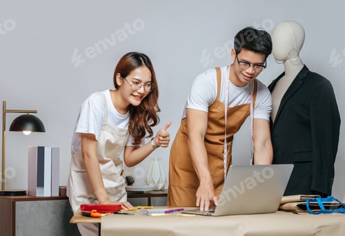 Preview: Young couple fashion designers working in studio