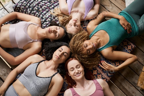 Preview: top view of carefree multiethnic girlfriends meditating on pillows with closed eyes, tranquility