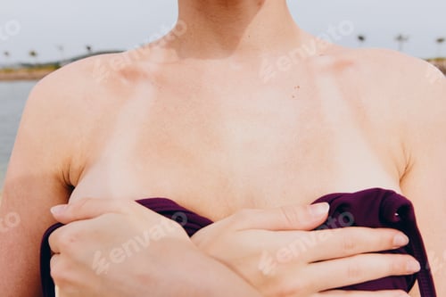 Preview: Woman with hands on chest standing in front of a peaceful body of water