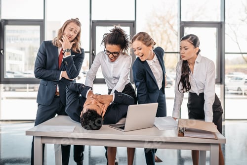 Preview: Three young angry businesswomen punishing businessman lying on table, business team meeting concept