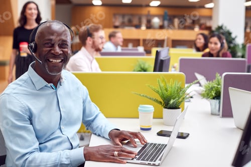 Preview: Portrait Of Mature Businessman Wearing Phone Headset Talking To Caller In Customer Services Centre
