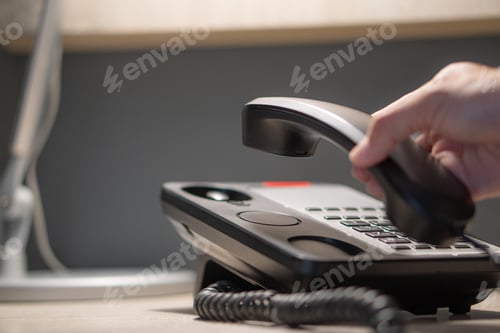 Preview: Photo of hands pressing button on black telephone