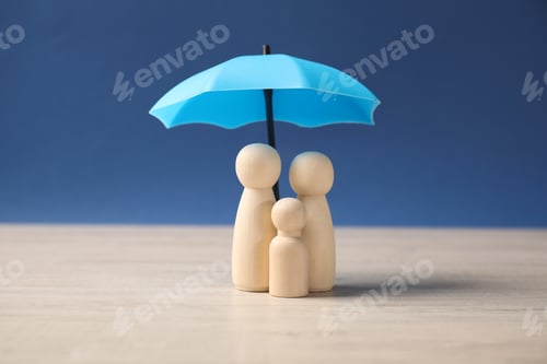 Preview: Human figures under umbrella on light wooden table against blue background. Insurance concept