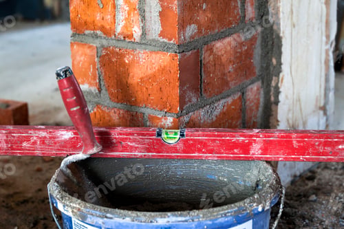 Preview: Close up of bricklaying industrial installing bricks on construction site wall with working tools
