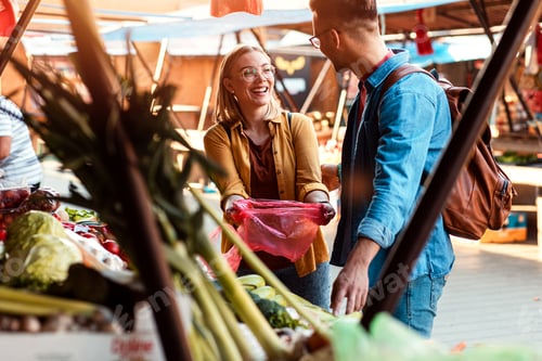 Preview: Young couple buying fresh vegetables on outdoor market.